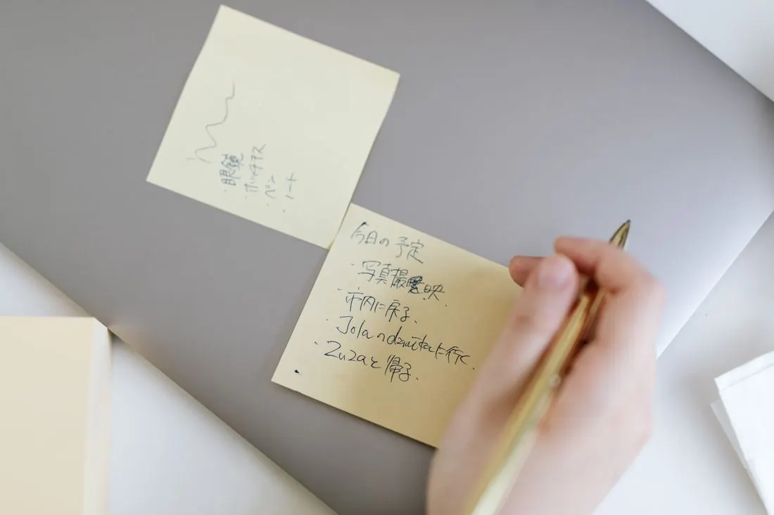 付箋に原稿のメモを書く手元（イメージ）