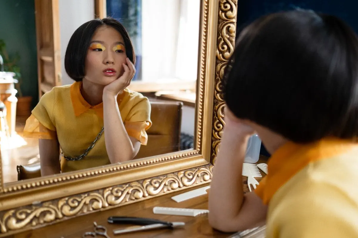 金色の額の鏡に向かう、ボブのスタイリスト
