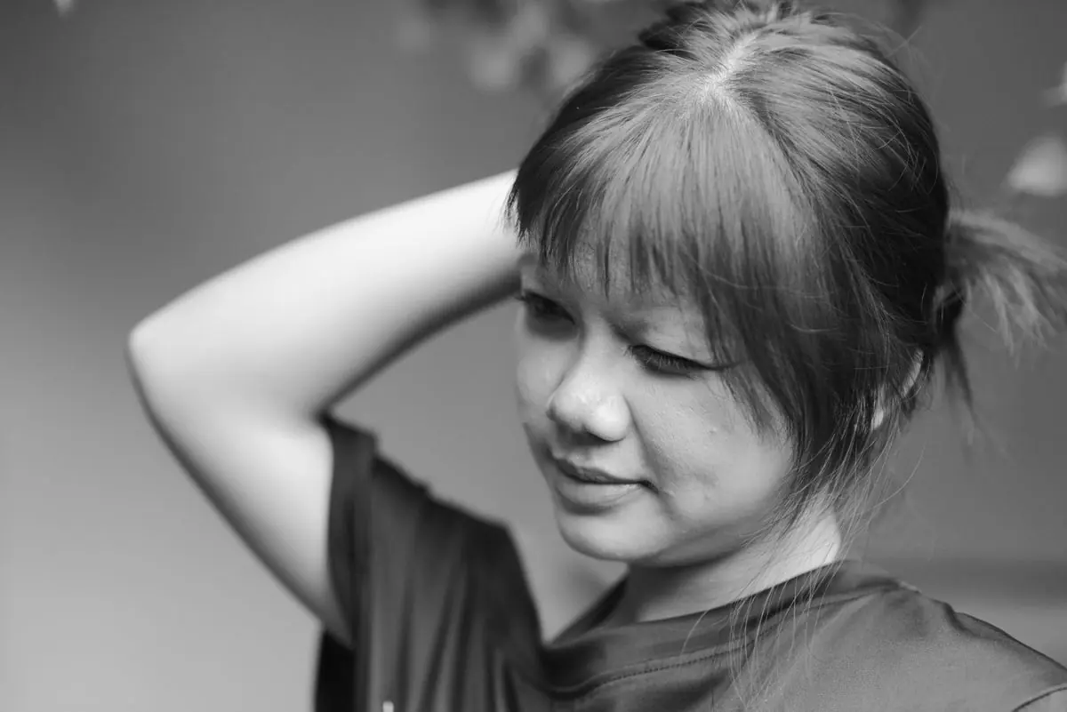 髪に手をあて、考えごとをする女性のモノクロ写真