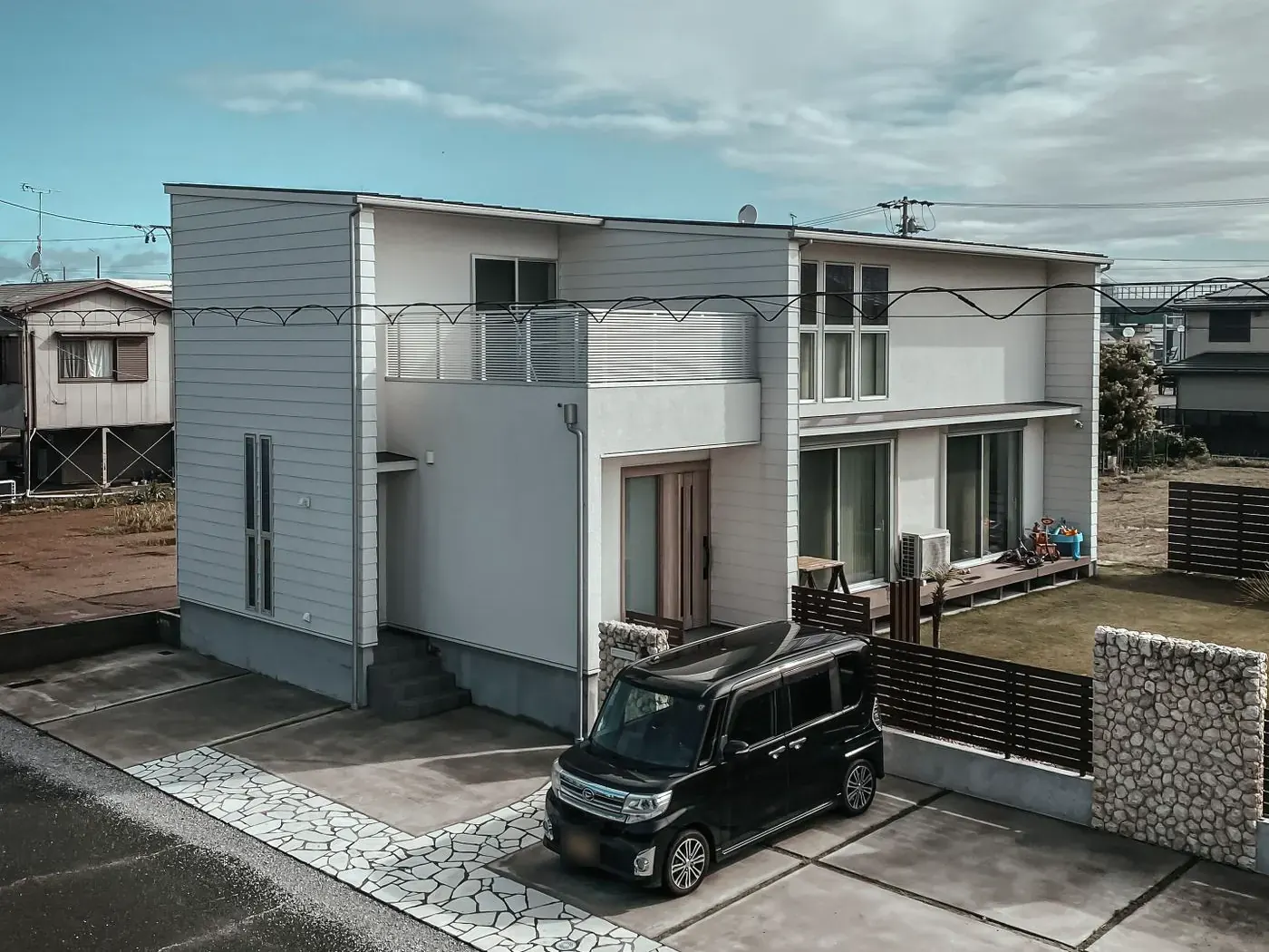白い外壁の新築の二階建て住宅と駐車スペース