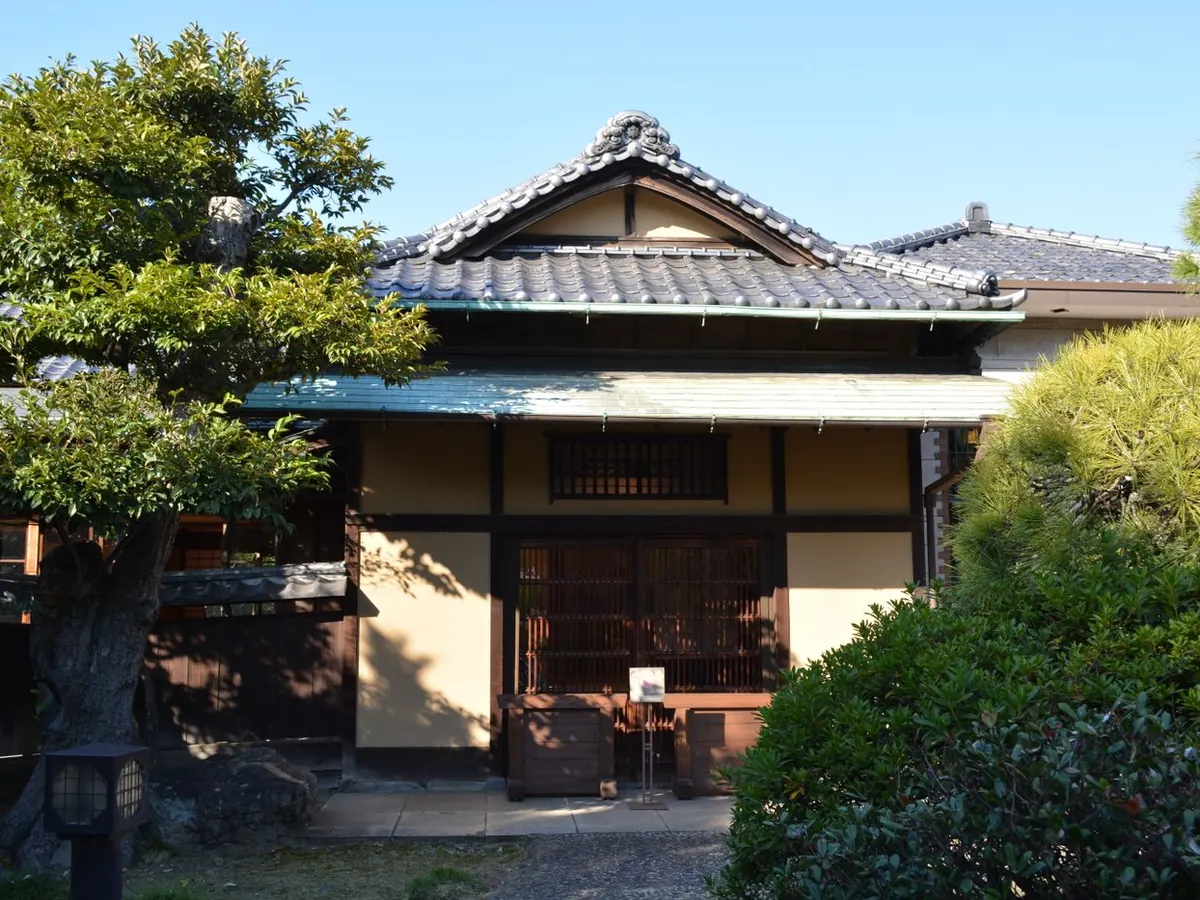 松の木のある、瓦屋根の平屋の住宅