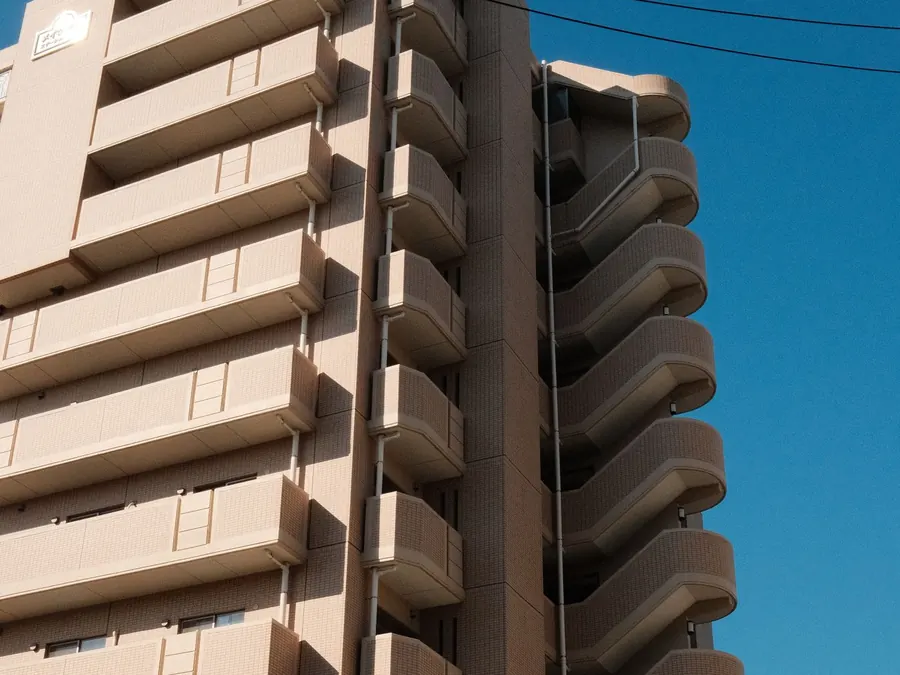 青空を背にしたベージュのマンション