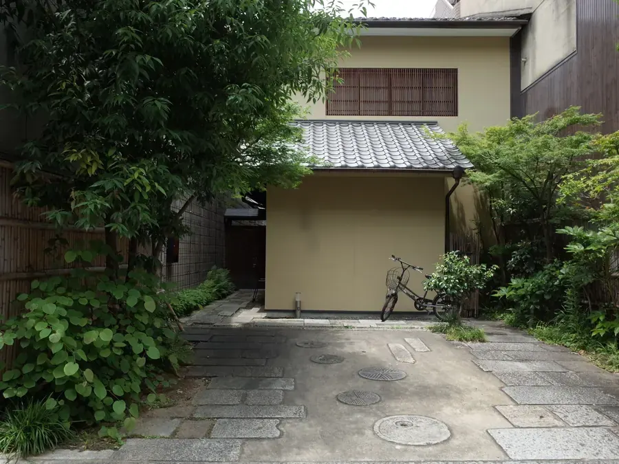 木々に囲まれた、瓦屋根の家の入り口