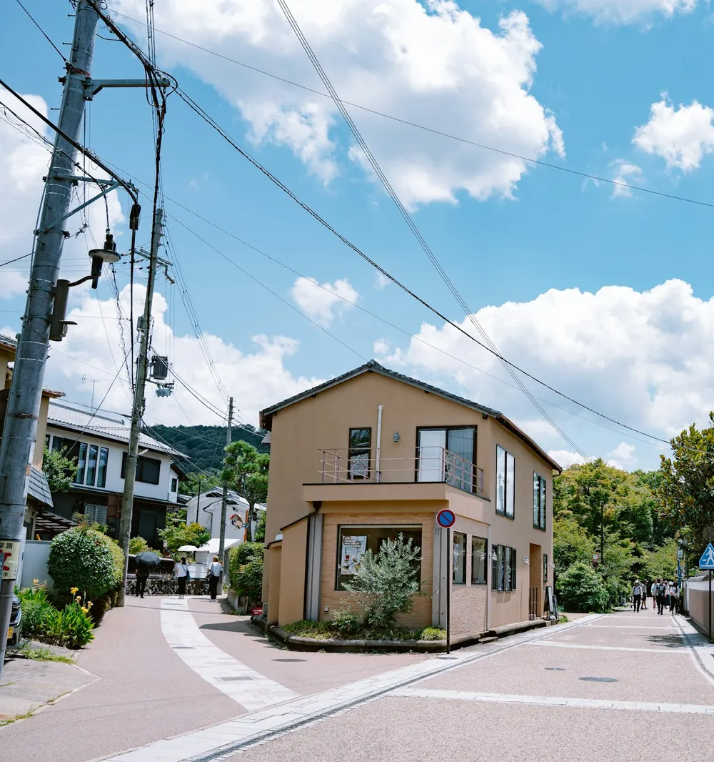 青空の下、角地に建つ二階建ての家と通り