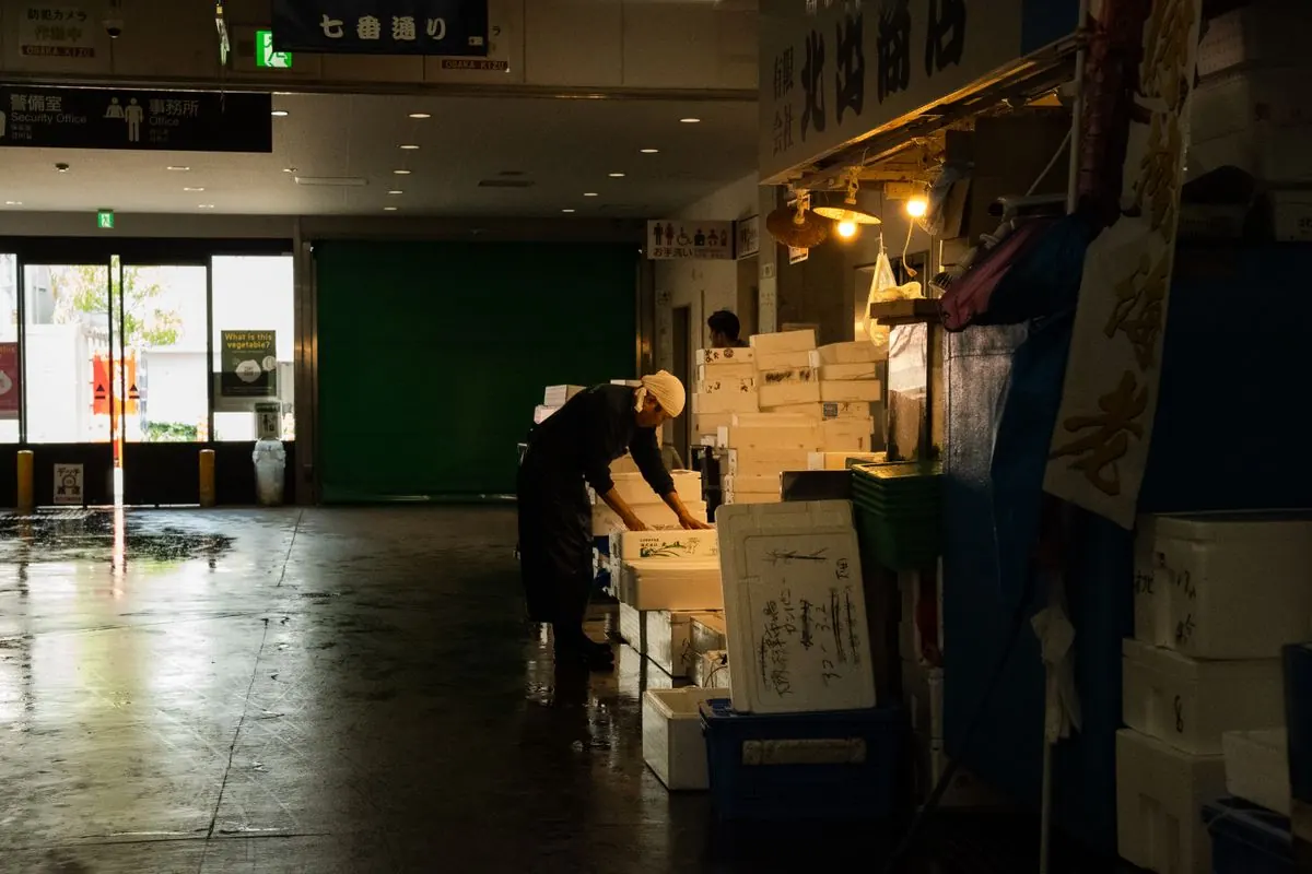 早朝の市場で、魚の箱を並べる人