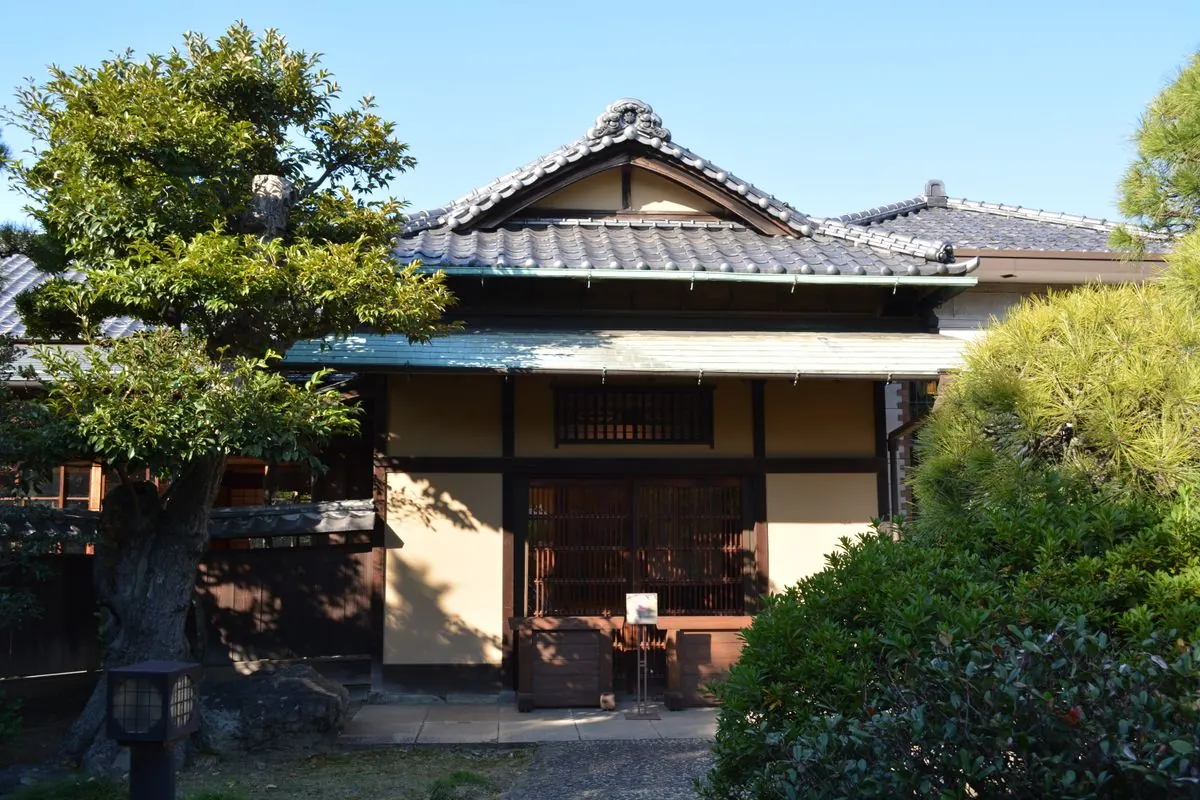 松の木の奥に建つ瓦屋根の古民家