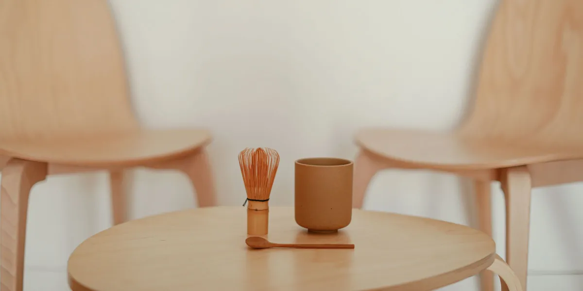 木のいす2脚と丸いテーブル、茶せんと湯のみを置いた待合スペース