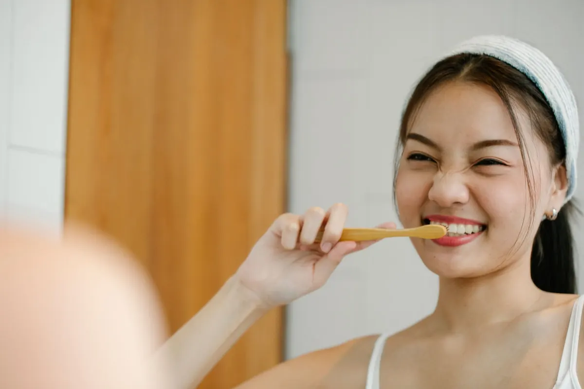 木の歯ブラシで歯をみがく女性
