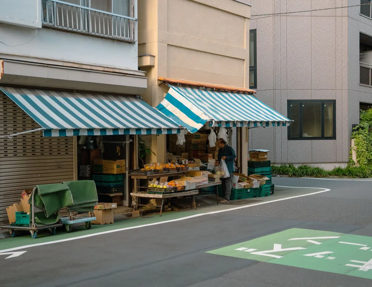 まちかどの八百屋の店先と、品物を整える店主